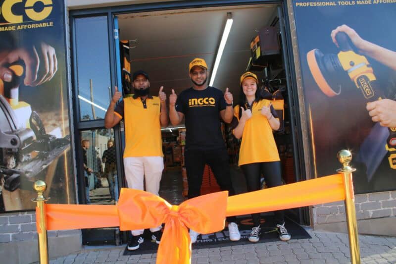 Photo of three people standing behind an orange bow