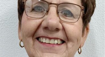 White woman with glasses and short hair.