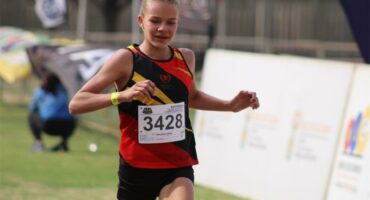 A photo of a girl in a red, yellow and black running kit, with the numbers 3428 on the front.