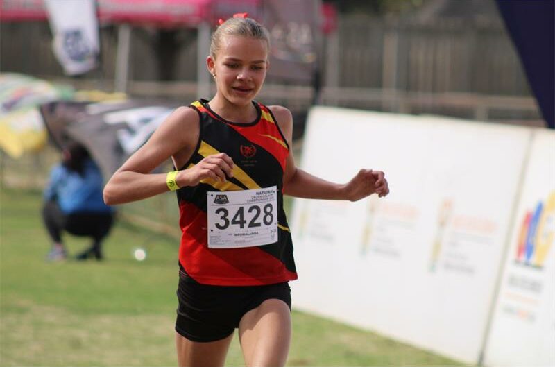 A photo of a girl in a red, yellow and black running kit, with the numbers 3428 on the front.