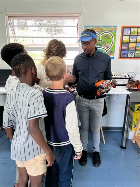 Man with blue cap show four children a robotics vehicle