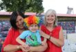 Two white women dressed in red with a boy