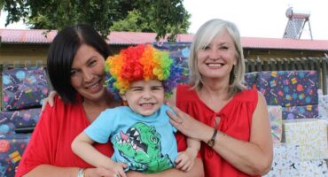 Two white women dressed in red with a boy