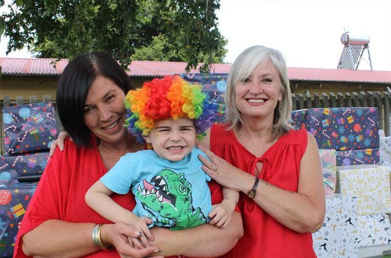 Two white women dressed in red with a boy