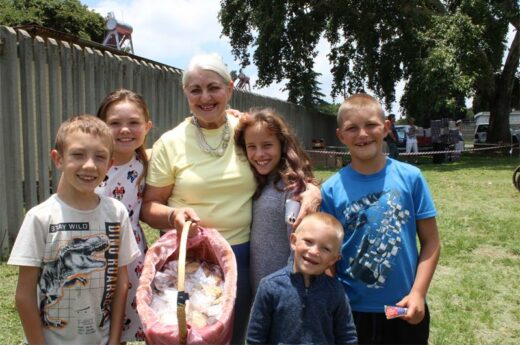 Grey-haired white woman surrounded by children