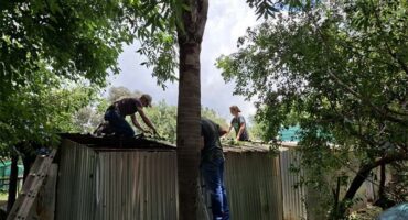 Three people working on a corrugated steel structure