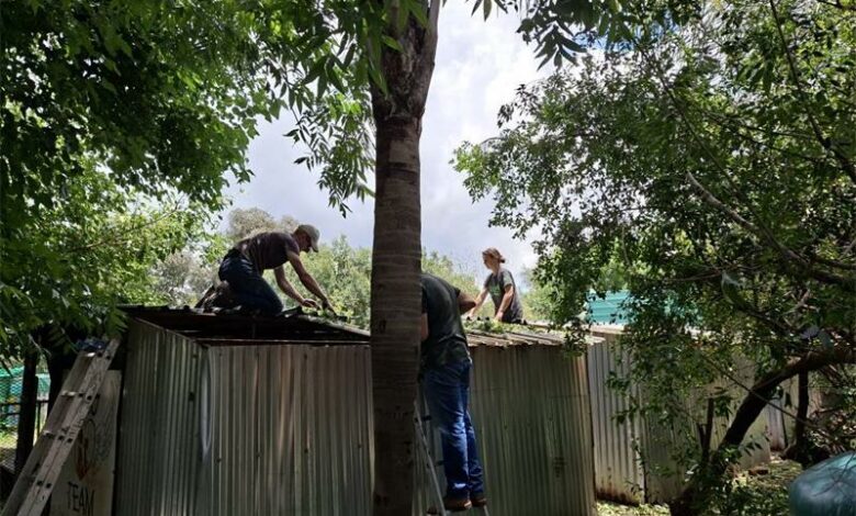 Three people working on a corrugated steel structure