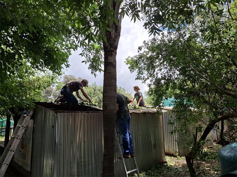 Three people working on a corrugated steel structure