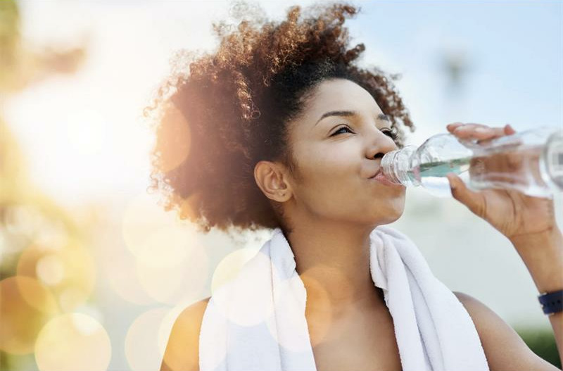 Brown woman drinking water from a bottle