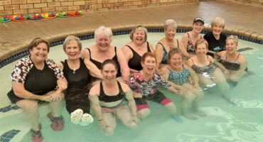 Twelve women sitting in a pool