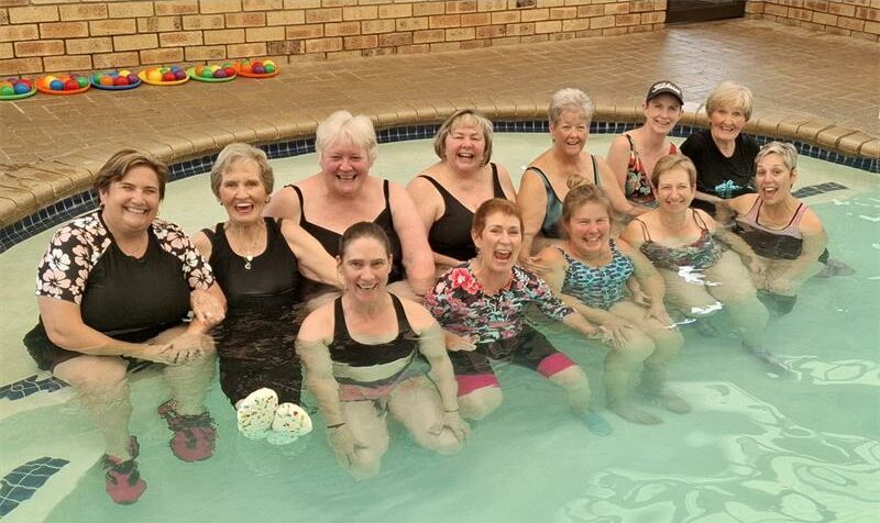 Twelve women sitting in a pool