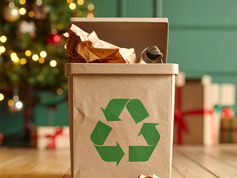 Recycling container standing in front of a Christmas tree