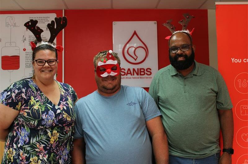 Three people, one woman and two men wearing Christmas costumes.
