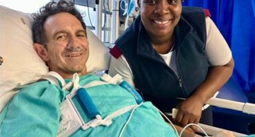 Man in hospital bed with a nurse standing next to him