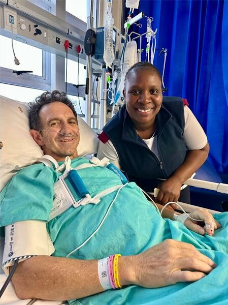 Man in hospital bed with a nurse standing next to him