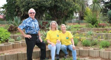 Man with sunglasses stand next to two women wearing yellow T-shirts.
