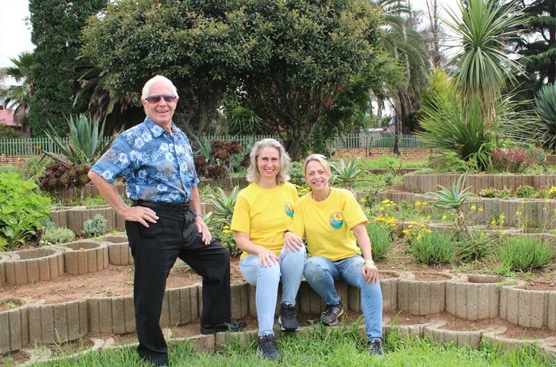 Man with sunglasses stand next to two women wearing yellow T-shirts.