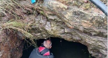 A man in a wetsuit sits inside a tunnel