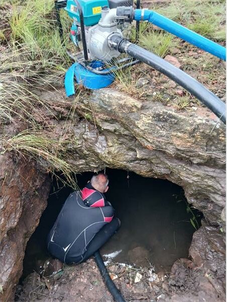 A man in a wetsuit sits inside a tunnel