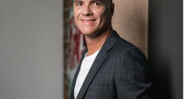 Man in black suit leaning against the wall