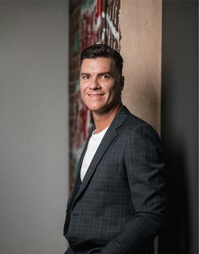 Man in black suit leaning against the wall
