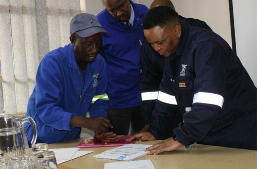 Black man in overalls shows papers to another man
