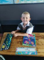 Blond white boy surrounded by stationery