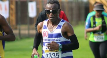 A photo of a man in a white and blue vest. He's wearing sunglasses.