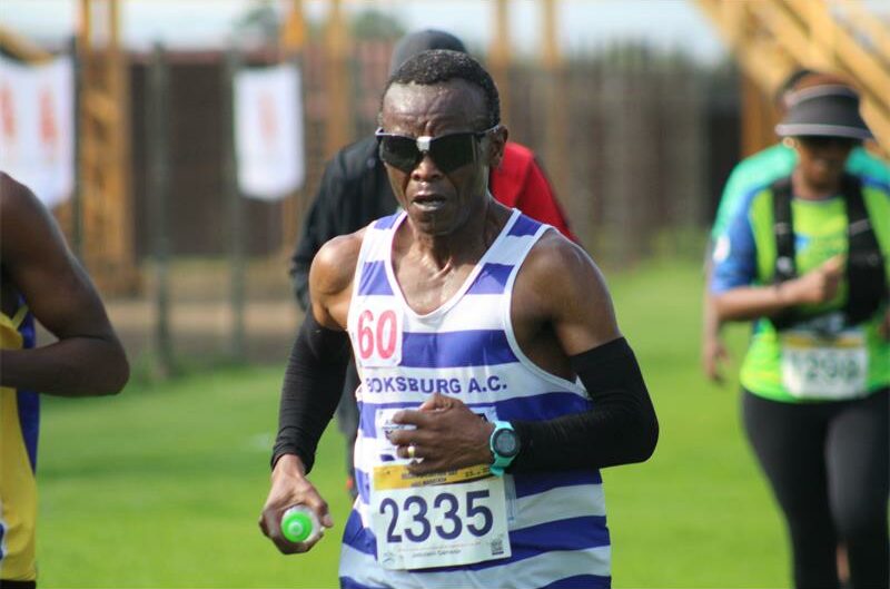 A photo of a man in a white and blue vest. He's wearing sunglasses.