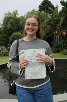 Meisie staan met 'n papier in haar hande