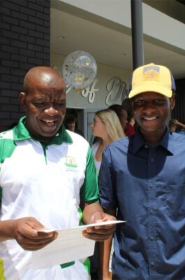Black man looks at paper with young black man smiling