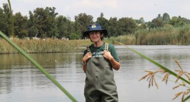 Woman wearing waterproof waders standing hip deep in water.