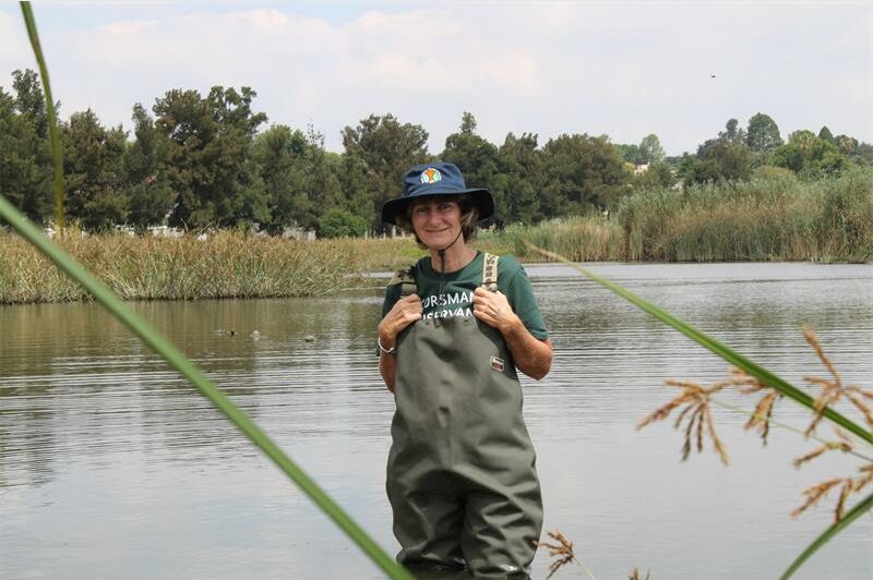 Woman wearing waterproof waders standing hip deep in water.