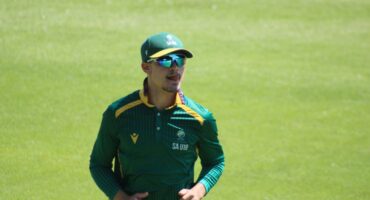 Man wearing a green sport's uniform and sunglasses