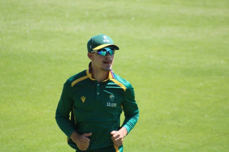 Man wearing a green sport's uniform and sunglasses