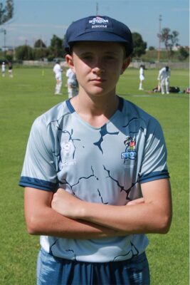 A photo of a boy wearing a cricket cap and a multicoloured Eastern Cricket Union shirt.