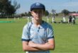 A photo of a boy wearing a cricket cap and a multicoloured Eastern Cricket Union shirt.
