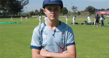 A photo of a boy wearing a cricket cap and a multicoloured Eastern Cricket Union shirt.