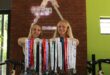 Two blonde women holding medals on their arms