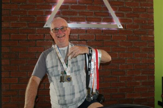 Elderly man smiles while holding medals
