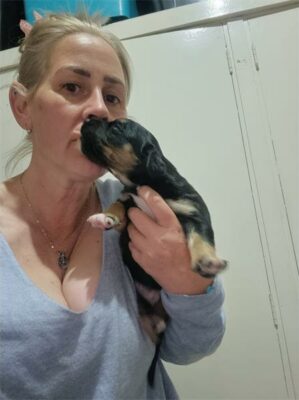 Blonde woman, kissing a black puppy