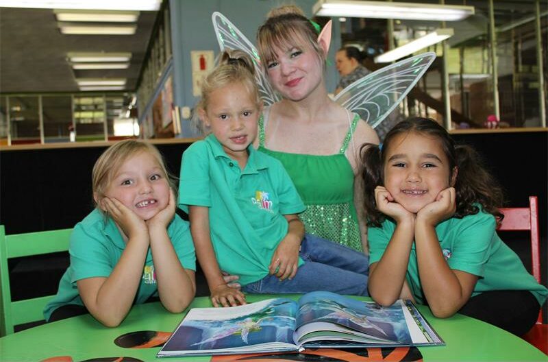Three girls wearing green golf shirts with a blonde girl dressed as a fairy