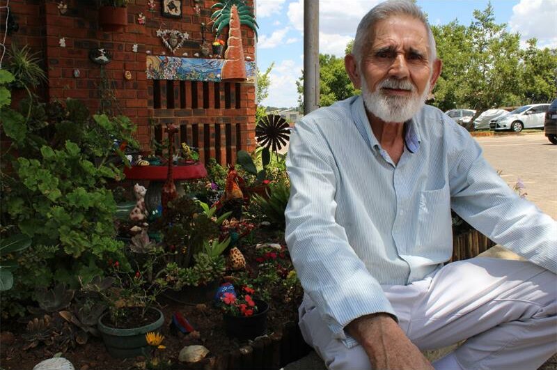 Old man sitting in front of a garden