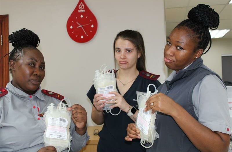 Three women pout while holding empty blood donor bags