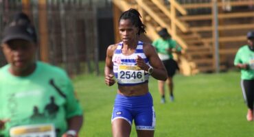 A photo of a runner in a blue and white vest and blue tights.