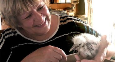 Woman smiling while holding a chick.