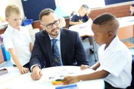 Man sits at a desk with a white and black boy