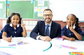 Man sits at a desk with a coloured and black girl