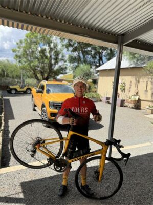 Man in cycling gear holding a bike