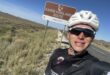 Cyclist standing in front of a brown road sign